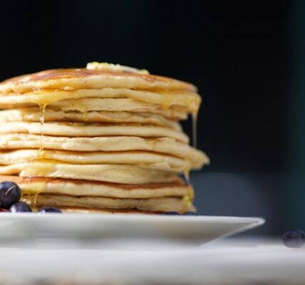 Stack of fluffy Japanese pancakes topped with whipped cream and fresh fruit in Tokyo café